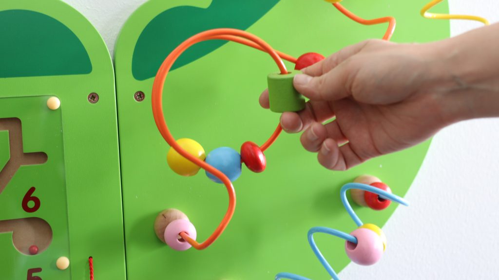 Vihreä lasten lelu, jossa on eri värisiä liikkuvia osia.