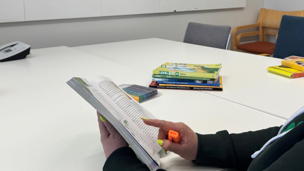 Henkilö osoittaa jotakin oppikirjassa.