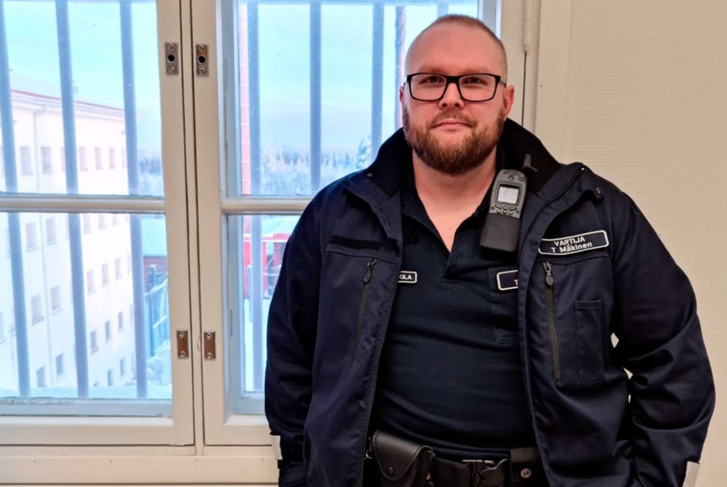 Miesvartija seisoo ikkunan edessä.