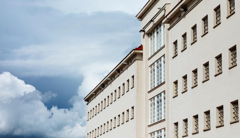 A wall of a building with windows on three floors. The windows have bars.