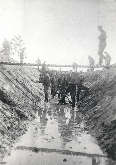 Mustavalkoinen kuva. Joukko miehiä kuivaamassa suota Köyliössä.