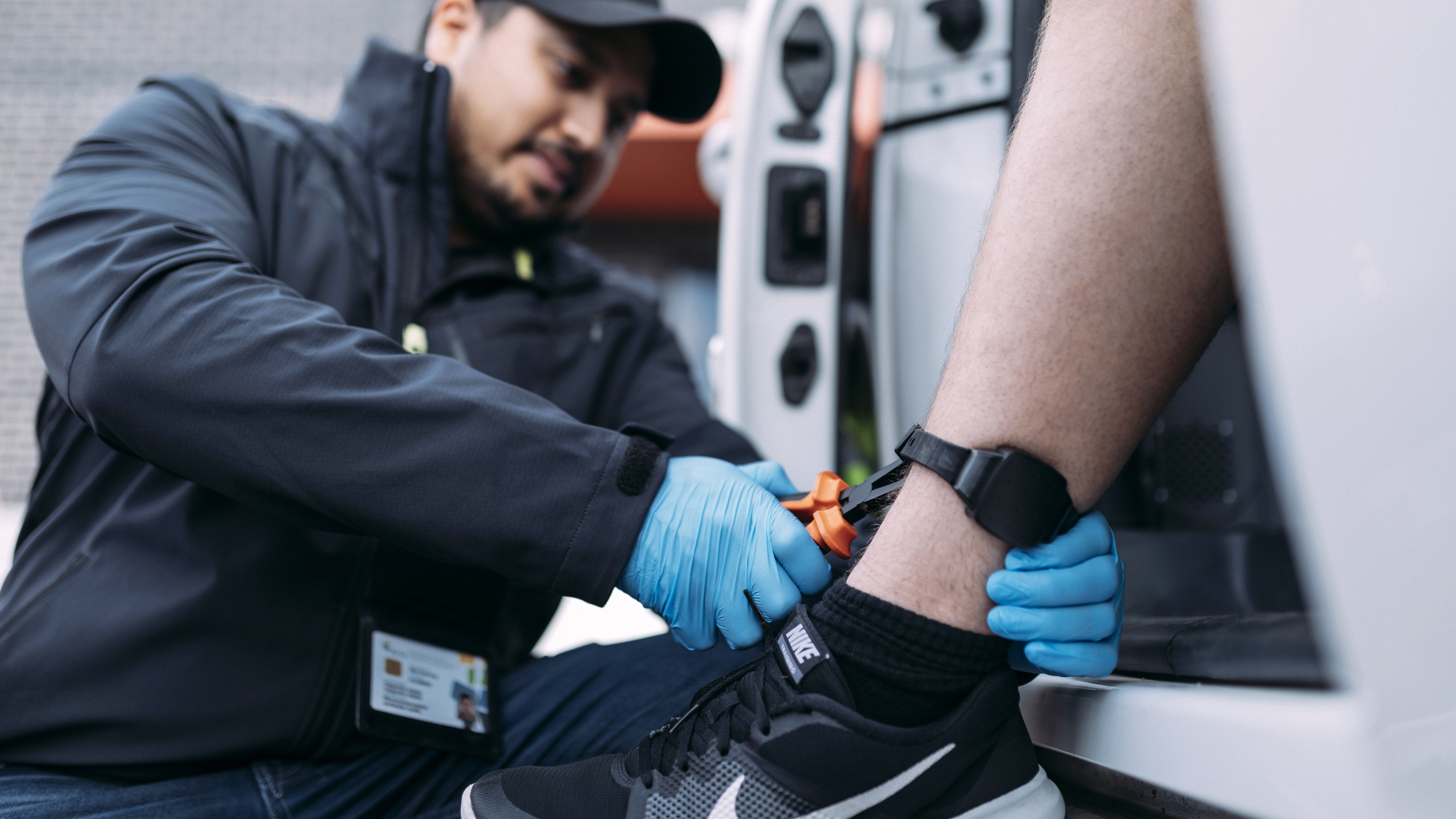 An official of the Prison and Probation Service fastens an ankle tag.