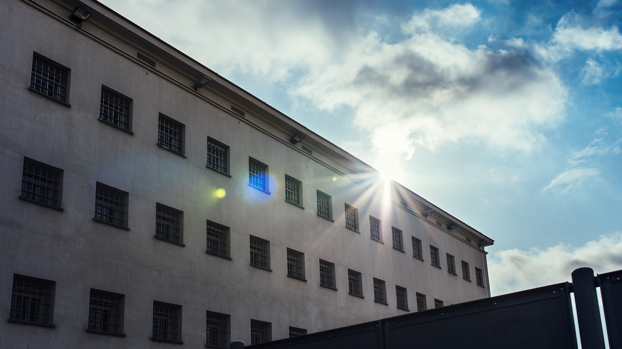 Vankilarakennuksen takaa paistaa aurinko.