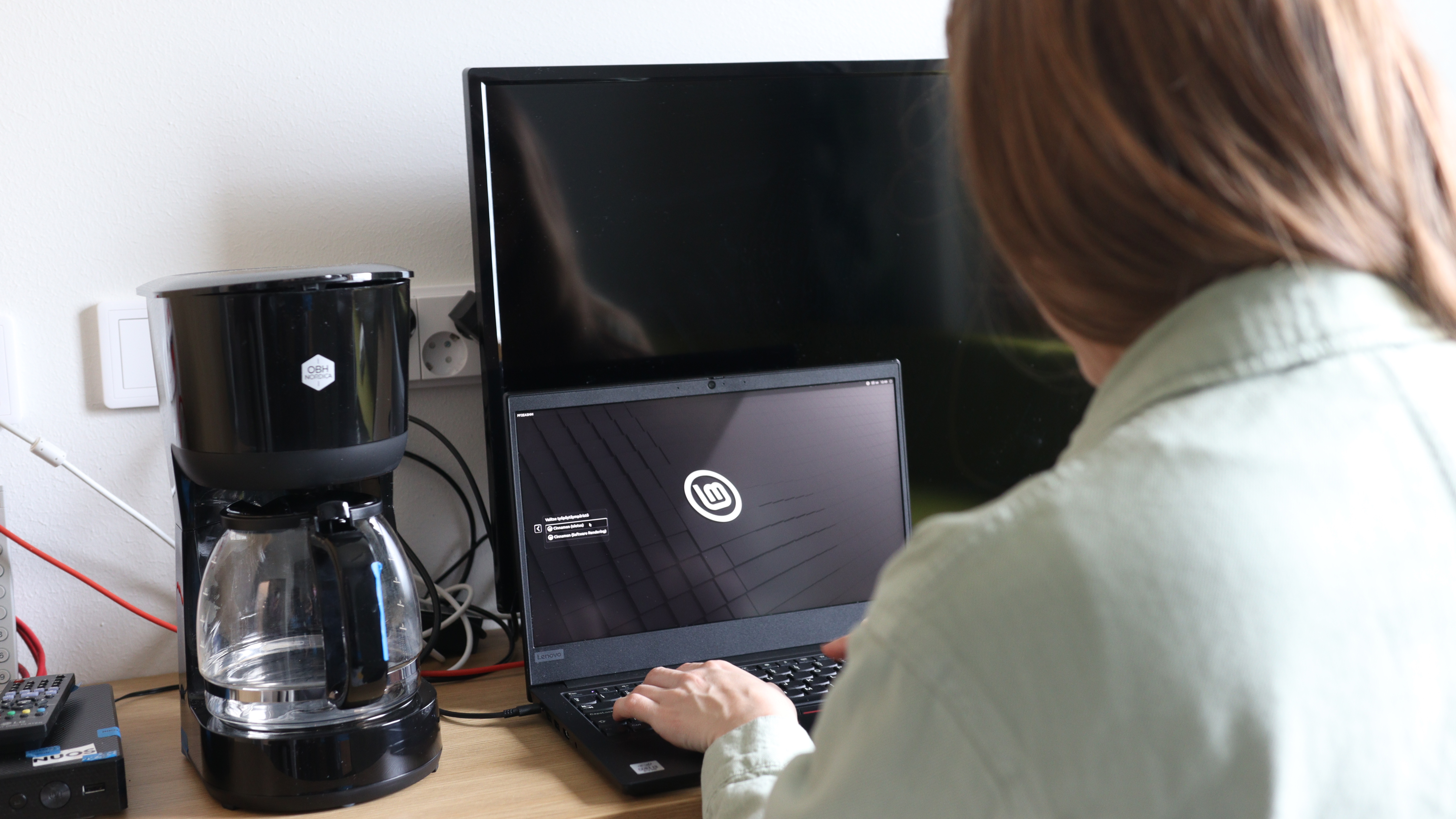 A woman wearing a green shirt sits on a computer.